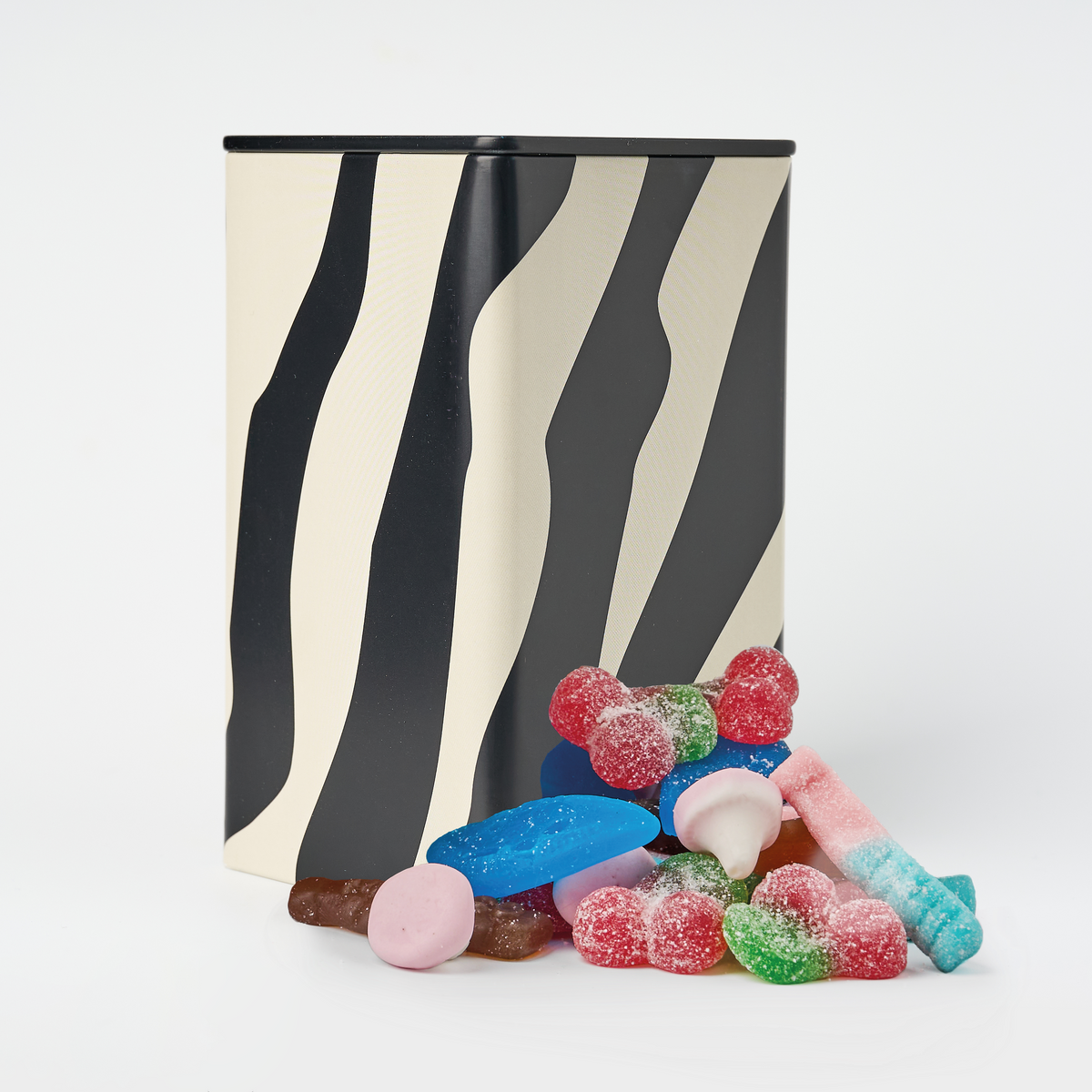 Zebra-striped black and white tall rectangular candy container with colorful swedish gummy candies on a white background